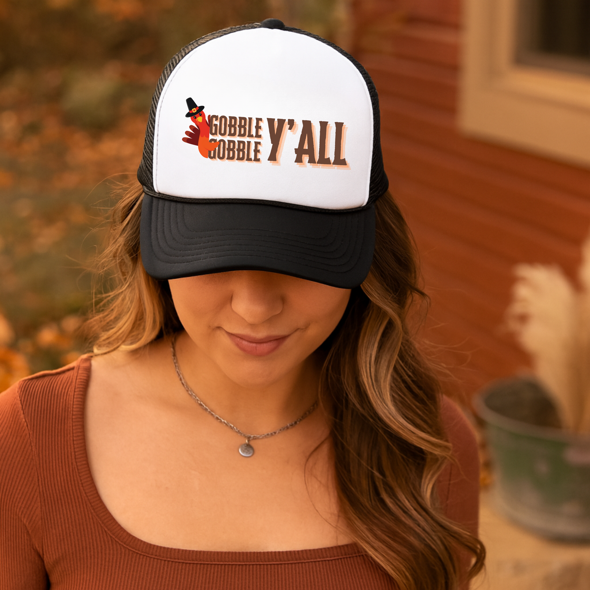 Woman wearing a 'Gobble Y'all' cap with a blurred outdoor background