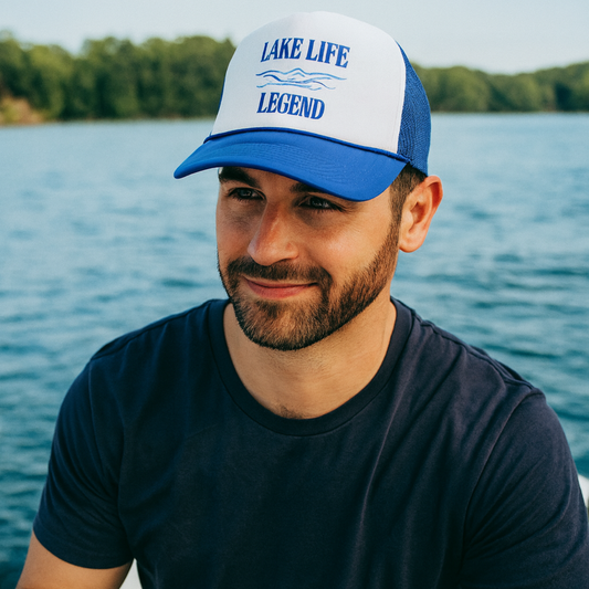 Man wearing a 'Lake Life Legend' cap by a lake