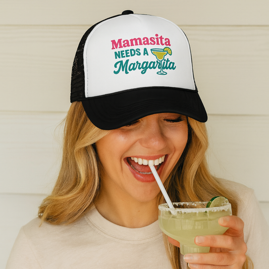 Woman wearing a cap with 'Mamasita Needs a Margarita' text, holding a drink.