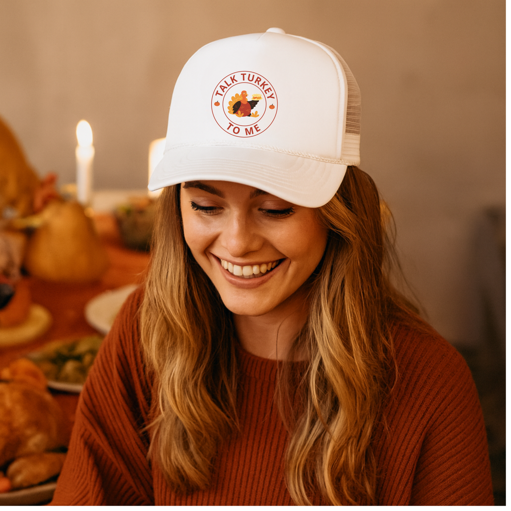Woman wearing a 'Talk Turkey to Me' cap at a Thanksgiving table.